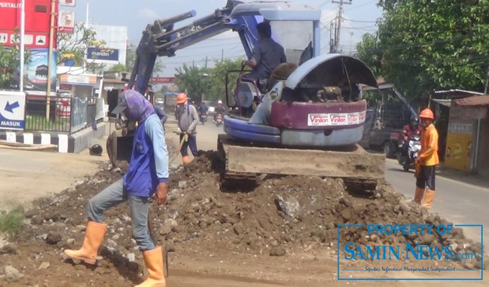 Sebuah ekskavator tengah mengeruk tanah lebih dari galian lubang pipa untuk kembali dipadatkan pada bekas galian pipa proyek Spam di pinggir jalan raya Wedarijaksa-Juwana.