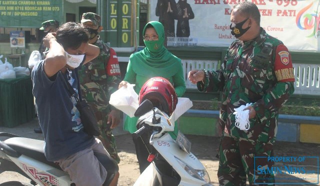 anramil 02 Juwana, Kapten Inf Sriyanto bersama istri saat membagikan nasi kotak kepada warga yang melintas di depan Koramil tersebut.(Foto:SN/dok-sri)