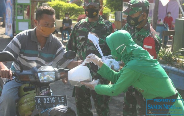  Ketua Persit KCK Cabang XXXIX Kodim 0718 Pati, Ny Iing Adi Ilham Zamani (ber tas pinggang hitam) didampingi Danramil 02 Juwana Kapten Inf Sriyanto saat membagikan nasi kotak kepada para pengguna jalan yang melintas.(Foto:SN/dok-sri)