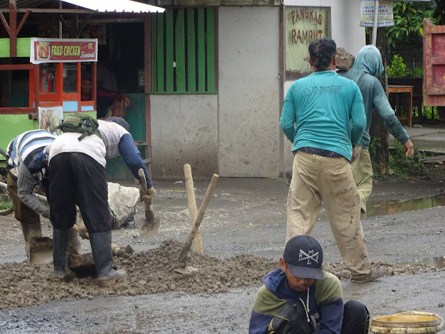 Para pekerja dari Bidang Binamarga DPUPR Kabupaten Pati, saat harus memperbaiki kerusakan ruas jalan di depan SPBU Ngantru, Desa Gajahmati, Kecamatan Pati, ada yang menggelar material, menggilas dan juga menguras genangan air di ruas jalan tersebut.(Foto:SN/aed)