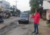 Aktivis GMNI Jepara, Yoga Bactiar (kanan/merah) menunjukkan ruas jalan Jepara-Bangsri yang rusak