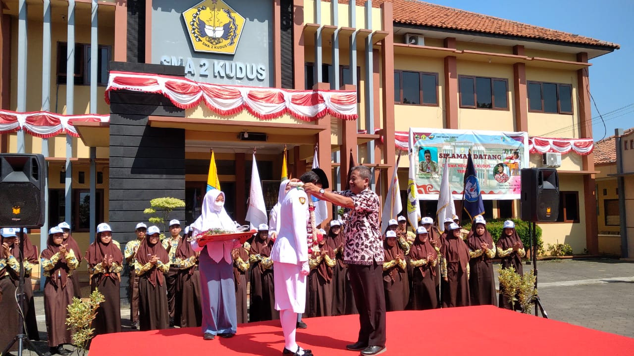 Foto: Firsty disambut Kepala Sekolah SMAN 2 Kudus Nur Afiffudin yang memberikan penyematan bunga, (Foto : Adam Naufaldo)