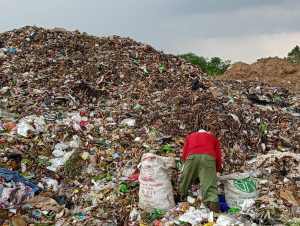 Tampak seseorang tengah mencari rosokan di tengah gunungan timbunan sampah di TPA Sukoharjo