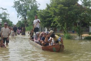 Sejumlah warga melintas di tengah genangan air