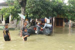 Tampak anak kecil melintas di tengah banjir