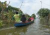 Tampak warga Kayen menaiki perahu akibat banjir yang merendam di tempatnya