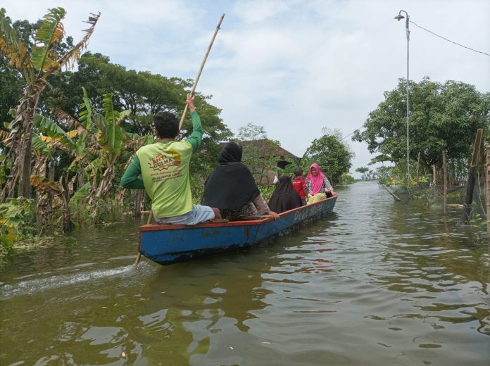 Tampak warga Kayen menaiki perahu akibat banjir yang merendam di tempatnya
