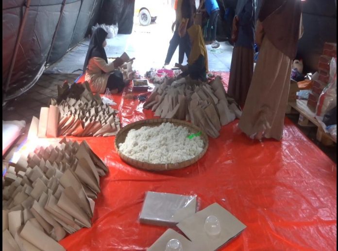 Tampak ibu-ibu relawan sedang mempersiapkan nasi bungkus bagi warga terdampak banjir