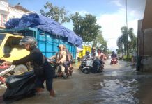 Foto: Tampak pengendara motor sedang berjuang melewati jalan banjir