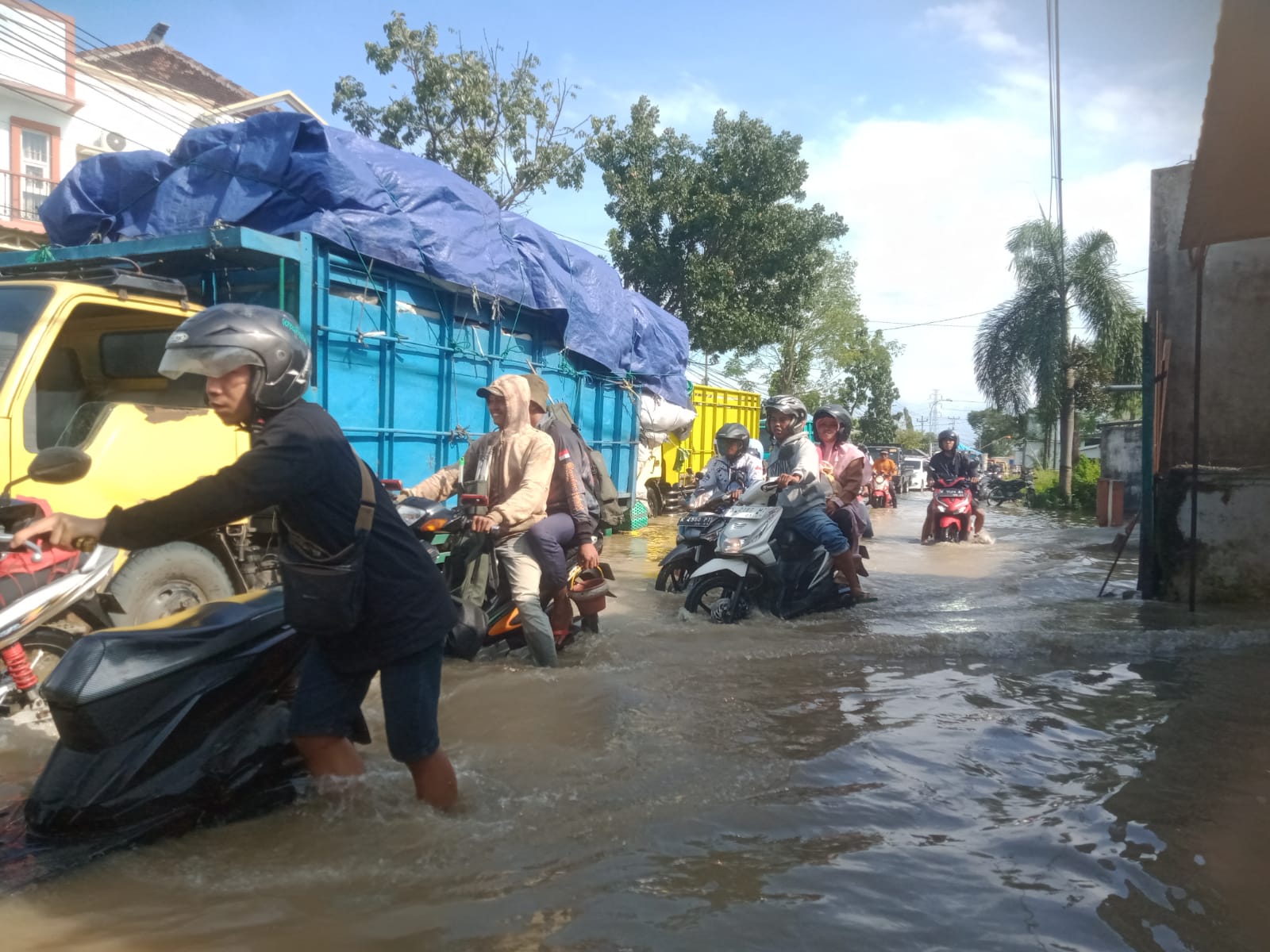 Foto: Tampak pengendara motor sedang berjuang melewati jalan banjir