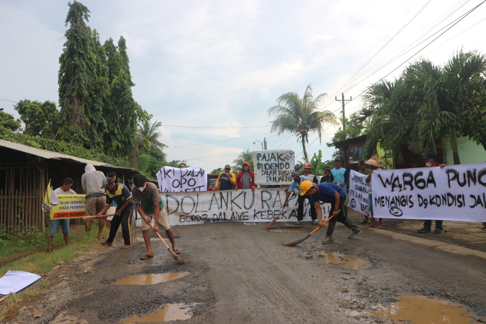 Sejumlah warga Desa Puncel melakukan bersih-bersih di jalanan sebagai bentuk protes mereka atas kerusakan jalan