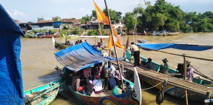 Warga saat menaiki perahu nelayan di atas Sungai Silugonggo Tayu saat pekan Syawalan/Lomban, Minggu (30/4/2023)